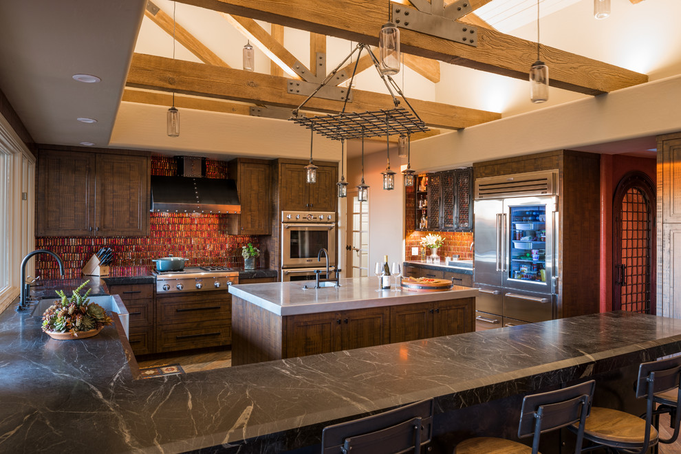 Contemporary u-shaped kitchen in Phoenix with a farmhouse sink, recessed-panel cabinets, dark wood cabinets, red splashback, mosaic tile splashback, stainless steel appliances, medium hardwood floors, with island, brown floor and black benchtop.