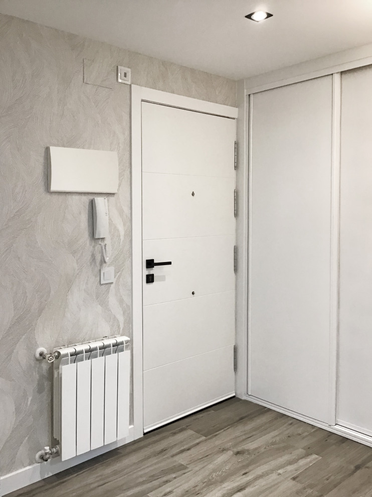 На фото: фойе среднего размера в современном стиле с серыми стенами, полом из ламината, белой входной дверью, серым полом и обоями на стенах