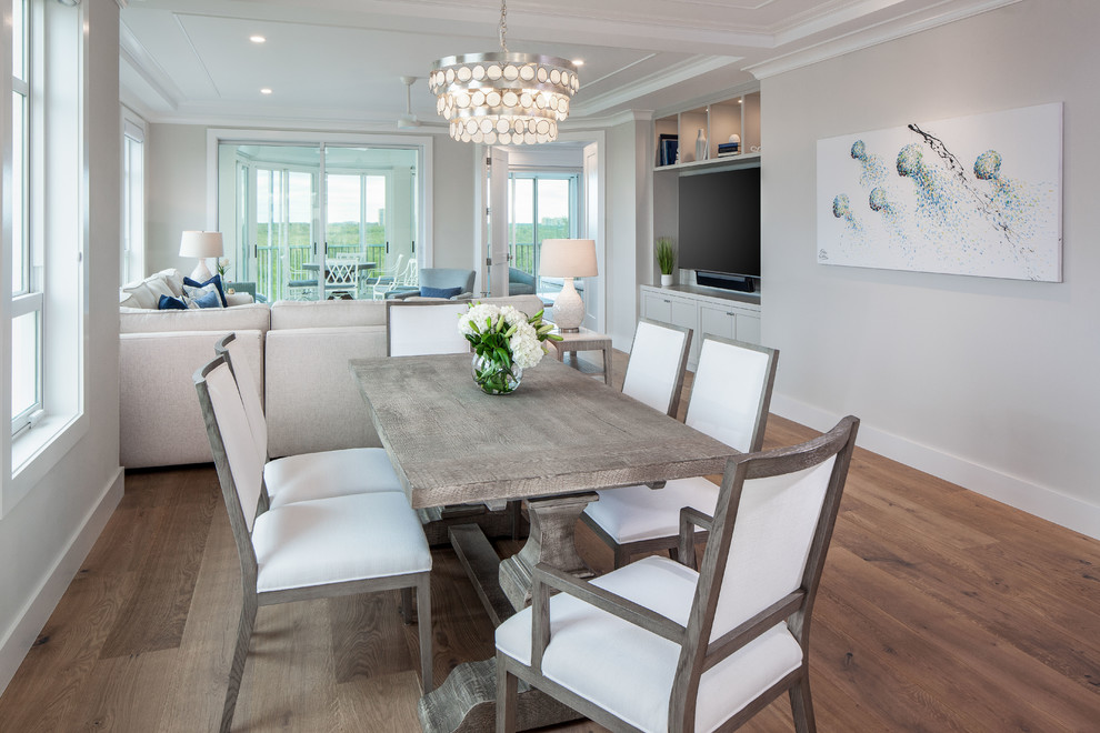 Photo of a mid-sized beach style open plan dining in Miami with white walls, light hardwood floors, no fireplace and brown floor.