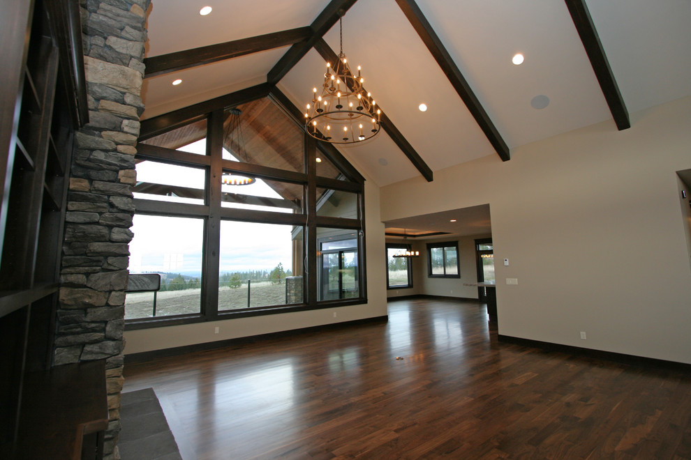 Inspiration for a large rustic open concept medium tone wood floor home design remodel in Seattle with beige walls, a standard fireplace, a stone fireplace and a wall-mounted tv