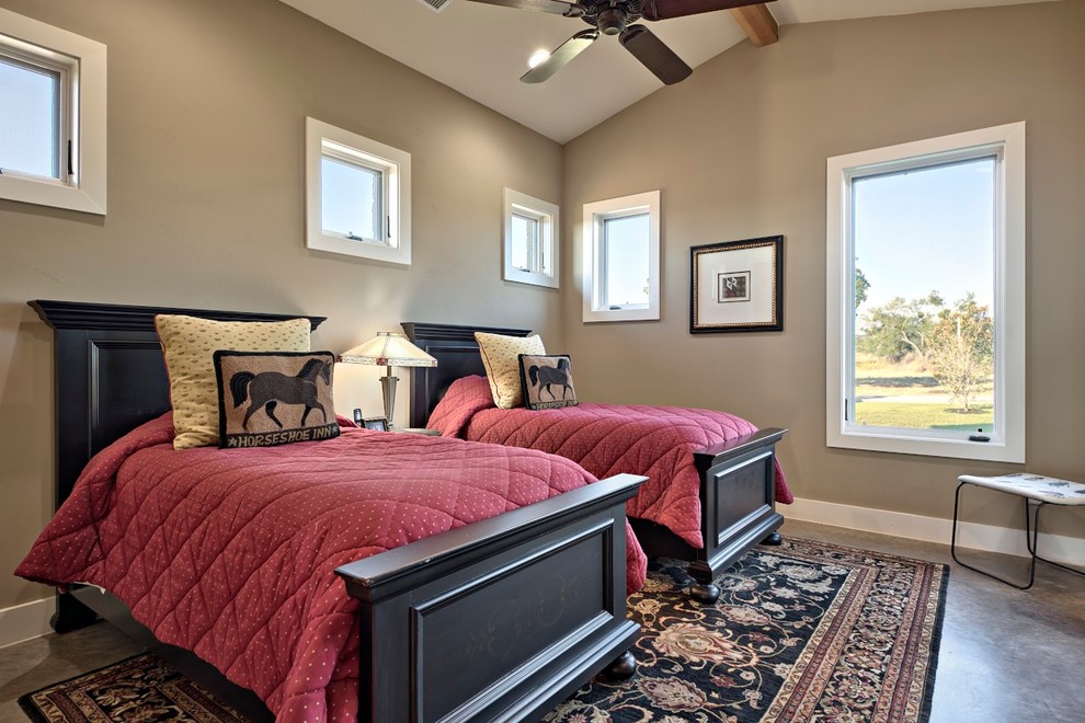 This is an example of a mid-sized country guest bedroom in Austin with beige walls and concrete floors.