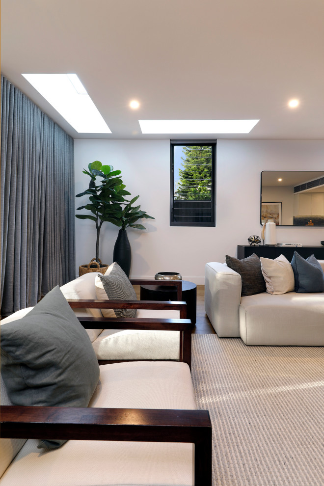 Design ideas for a mid-sized contemporary open concept living room in Sydney with white walls, light hardwood floors and a freestanding tv.