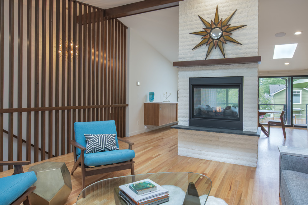 This is an example of a mid-sized midcentury open concept family room in Seattle with medium hardwood floors, a two-sided fireplace, a stone fireplace surround and vaulted.