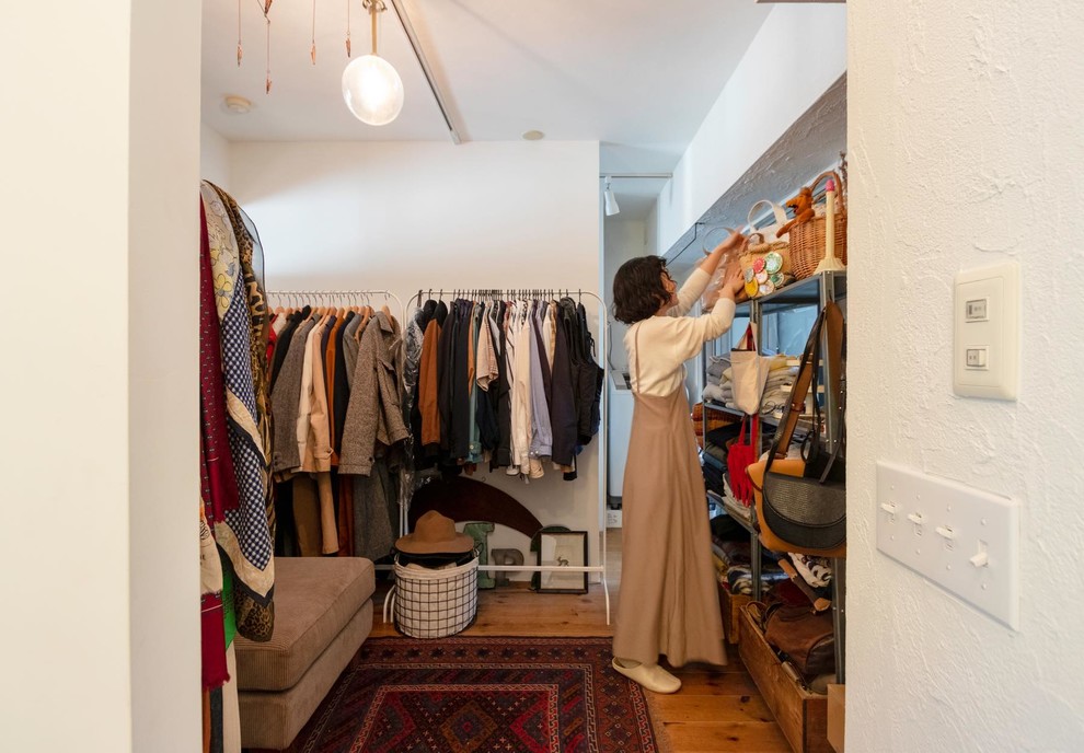 Asian gender-neutral walk-in wardrobe in Tokyo with open cabinets, medium hardwood floors and brown floor.