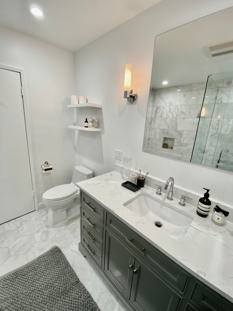 Photo of a medium sized classic ensuite bathroom in Los Angeles with freestanding cabinets, grey cabinets, an alcove bath, a corner shower, a one-piece toilet, white tiles, marble tiles, white walls, marble flooring, a submerged sink, engineered stone worktops, white floors, a hinged door, white worktops, a wall niche, a single sink and a freestanding vanity unit.