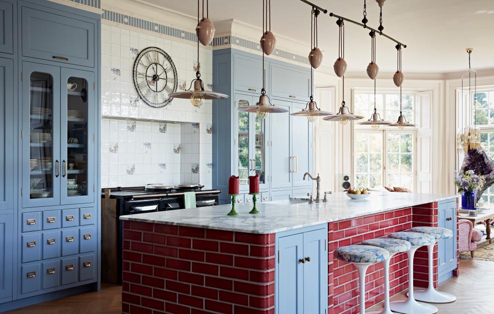 Eclectic kitchen in Hampshire with an integrated sink, glass-front cabinets, blue cabinets, marble benchtops, ceramic splashback, black appliances, light hardwood floors and with island.