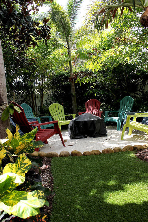 Design ideas for a small beach style backyard partial sun xeriscape for winter in Miami with a fire feature and natural stone pavers.