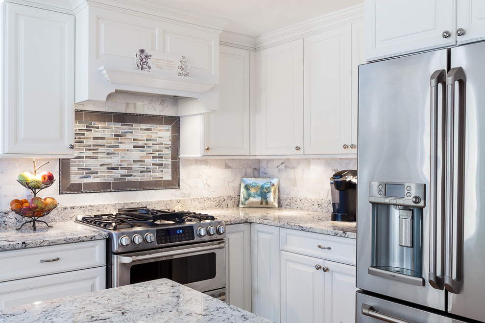 Photo of a large traditional l-shaped eat-in kitchen in Boston with an undermount sink, raised-panel cabinets, white cabinets, granite benchtops, grey splashback, stone tile splashback, stainless steel appliances, light hardwood floors and with island.