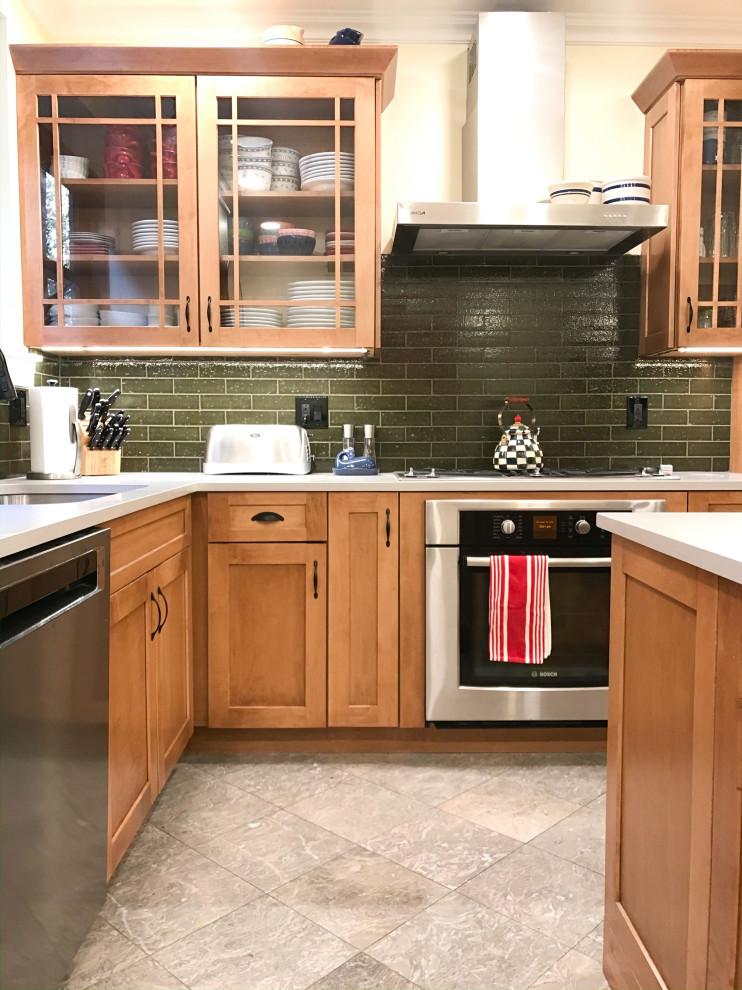 Eat-in kitchen - mid-sized transitional l-shaped eat-in kitchen idea in Chicago with an undermount sink, shaker cabinets, brown cabinets, green backsplash, stainless steel appliances, an island and gray countertops