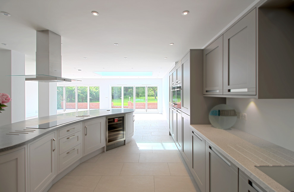 Design ideas for a large contemporary l-shaped open plan kitchen in Essex with an integrated sink, shaker cabinets, grey cabinets, solid surface benchtops, white splashback, black appliances, ceramic floors and with island.