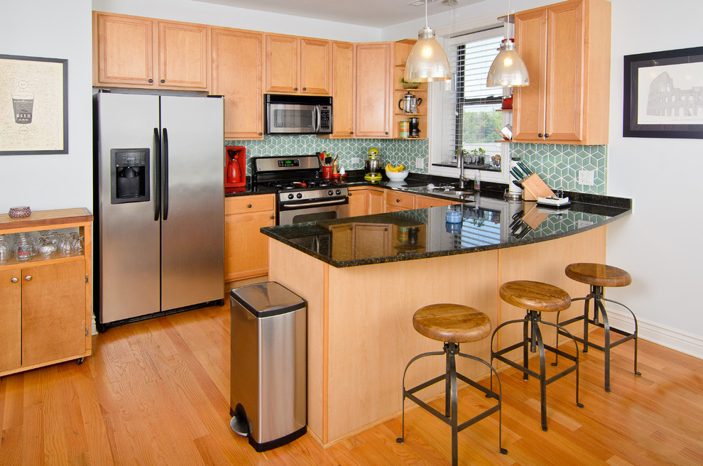 Inspiration for a mid-sized transitional u-shaped medium tone wood floor eat-in kitchen remodel in Chicago with an undermount sink, raised-panel cabinets, medium tone wood cabinets, granite countertops, green backsplash, porcelain backsplash, stainless steel appliances and a peninsula