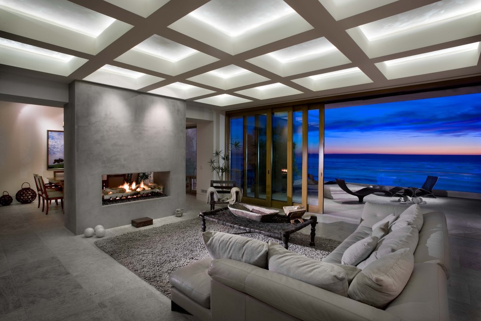 Design ideas for a contemporary living room in Orange County with a two-sided fireplace, grey walls and grey floor.