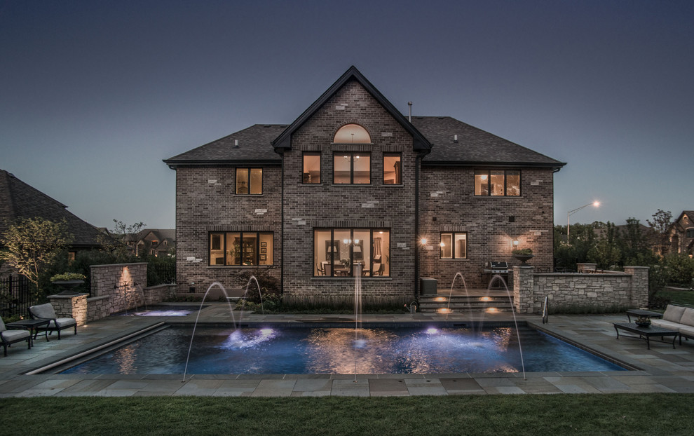 Inspiration for a mid-sized traditional backyard rectangular pool in Chicago with a hot tub and natural stone pavers.