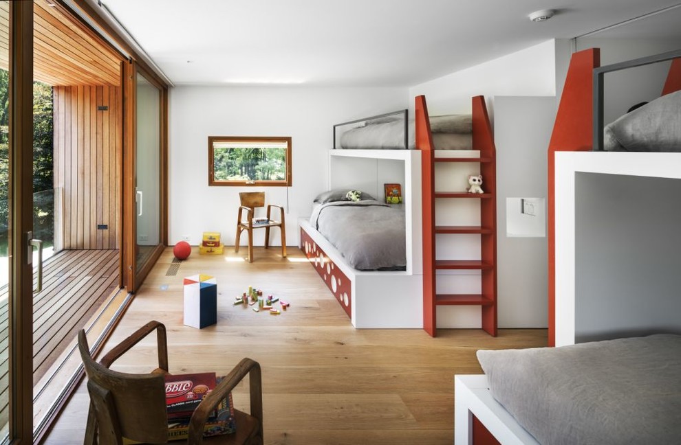 Photo of a modern gender-neutral kids' bedroom for kids 4-10 years old in New York with white walls and light hardwood floors.
