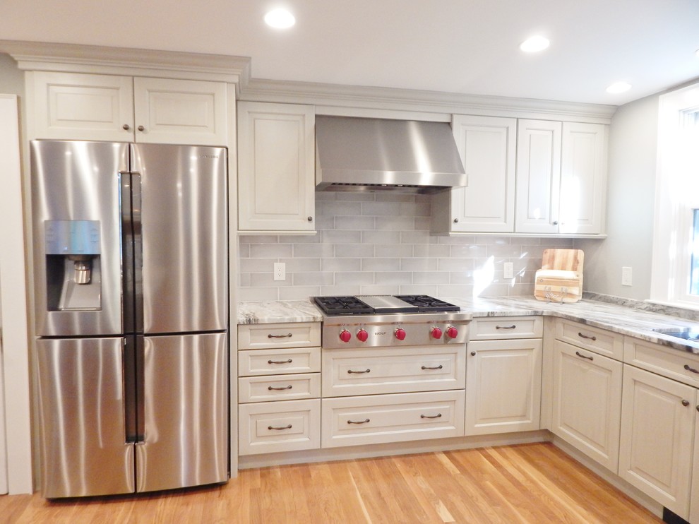 Mid-sized transitional l-shaped light wood floor open concept kitchen photo in Boston with an undermount sink, raised-panel cabinets, white cabinets, quartzite countertops, stainless steel appliances and an island