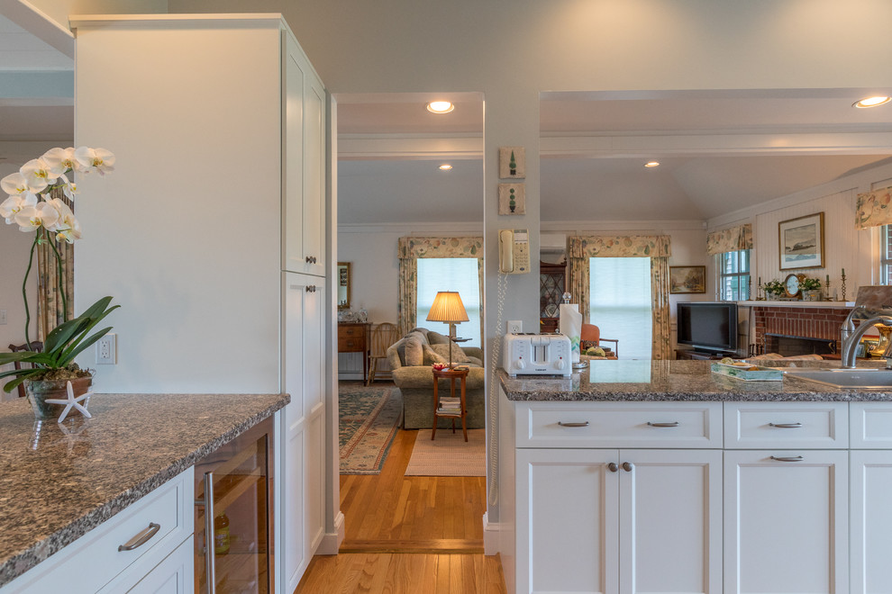 This is an example of a large transitional galley separate kitchen in Burlington with a drop-in sink, recessed-panel cabinets, white cabinets, granite benchtops, stainless steel appliances, medium hardwood floors, no island and brown floor.