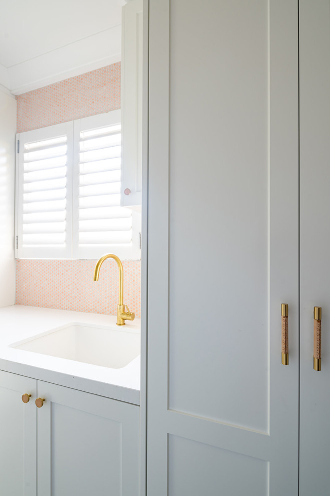 Idee per una sala lavanderia tradizionale di medie dimensioni con lavello sottopiano, ante in stile shaker, paraspruzzi rosa, paraspruzzi con piastrelle in ceramica e lavatrice e asciugatrice a colonna