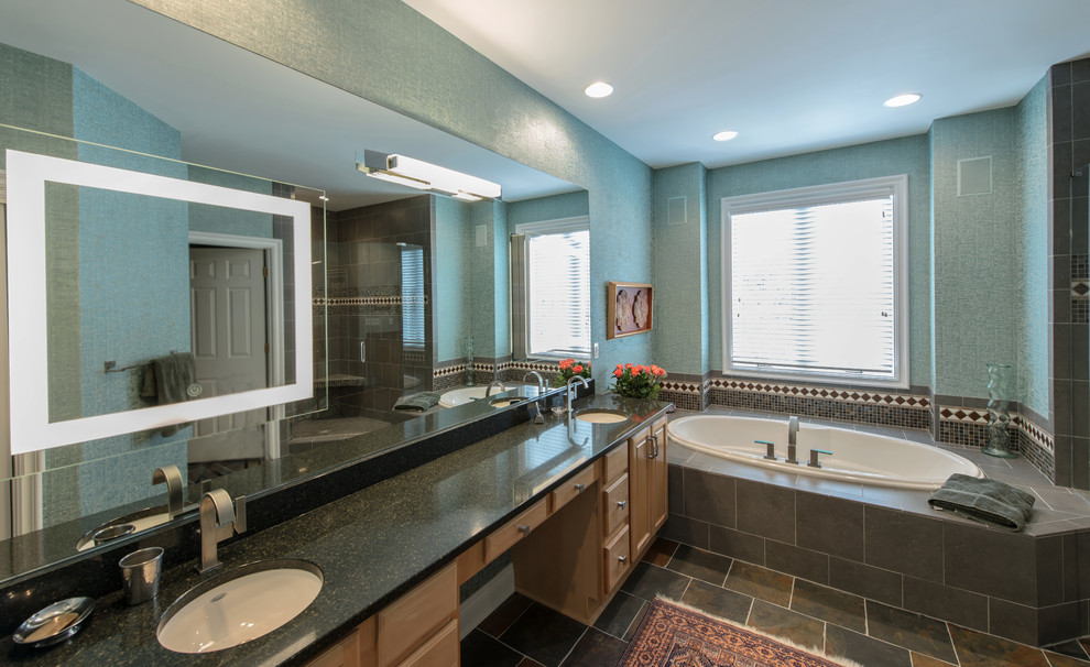 Photo of a large eclectic master bathroom in Cincinnati with raised-panel cabinets, light wood cabinets, an alcove tub, a corner shower, a one-piece toilet, beige tile, blue tile, brown tile, gray tile, multi-coloured tile, cement tile, green walls, travertine floors, an undermount sink and limestone benchtops.