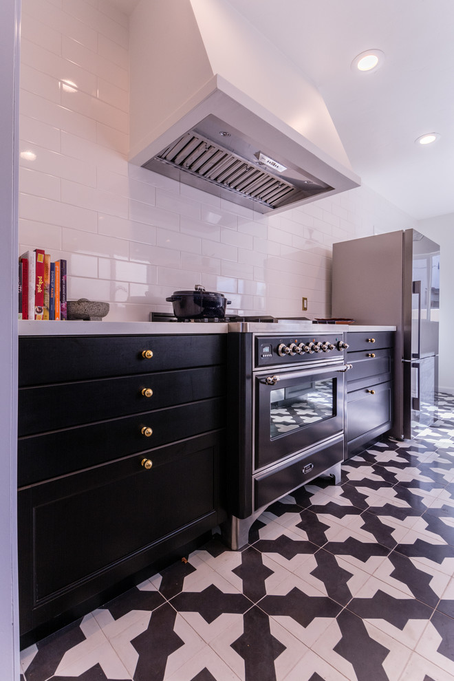 Inspiration for a mid-sized modern single-wall open plan kitchen in San Diego with an undermount sink, shaker cabinets, black cabinets, solid surface benchtops, white splashback, subway tile splashback, stainless steel appliances and porcelain floors.
