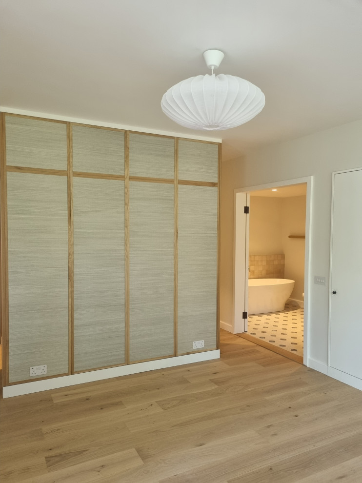 Bedroom - large modern master plywood floor bedroom idea in London with beige walls