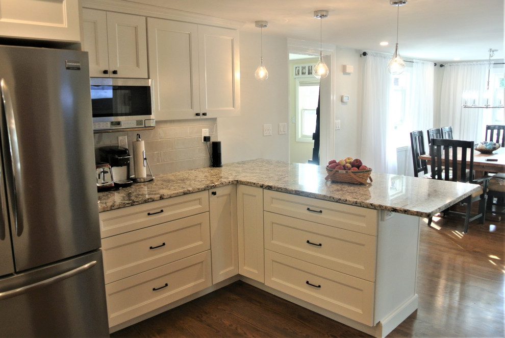 Transitional l-shaped medium tone wood floor and brown floor eat-in kitchen photo in Boston with an undermount sink, shaker cabinets, white cabinets, granite countertops, beige backsplash, subway tile backsplash, stainless steel appliances, an island and beige countertops