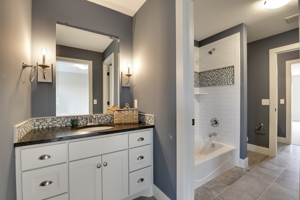This is an example of a large transitional kids bathroom in Minneapolis with an undermount sink, recessed-panel cabinets, white cabinets, an alcove tub, a double shower, a one-piece toilet, white tile, stone tile, blue walls and porcelain floors.