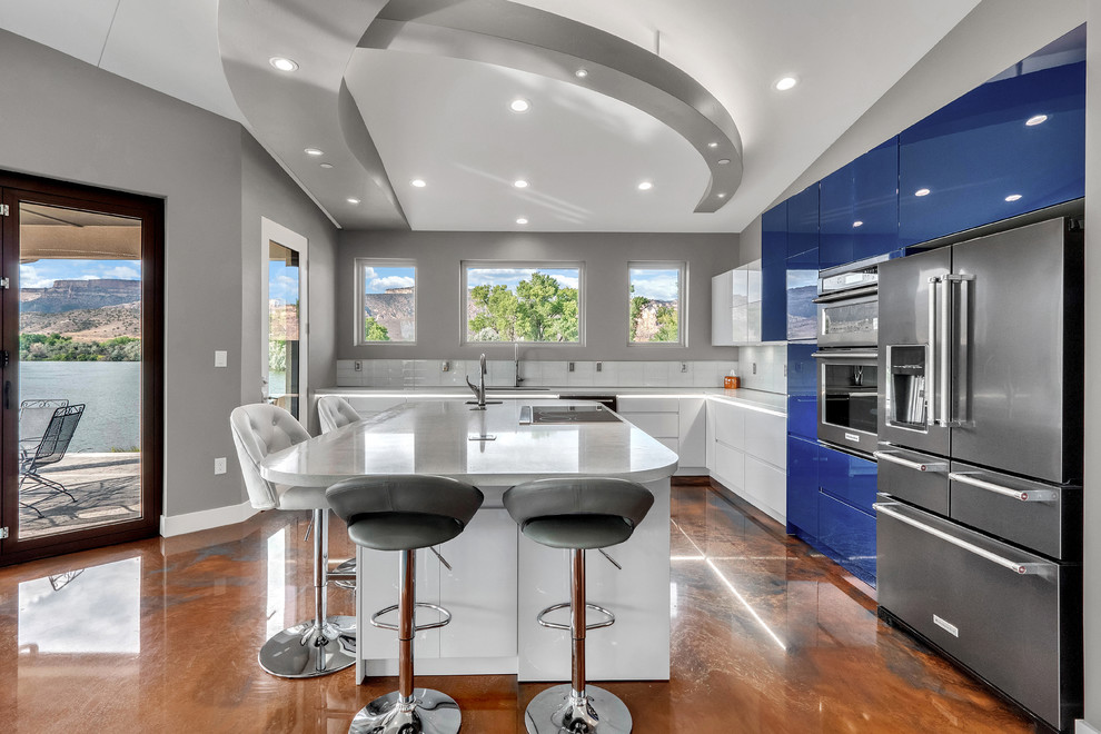 Inspiration for a mid-sized contemporary l-shaped eat-in kitchen in Denver with an undermount sink, blue cabinets, quartzite benchtops, white splashback, subway tile splashback, stainless steel appliances, concrete floors, with island, multi-coloured floor and white benchtop.