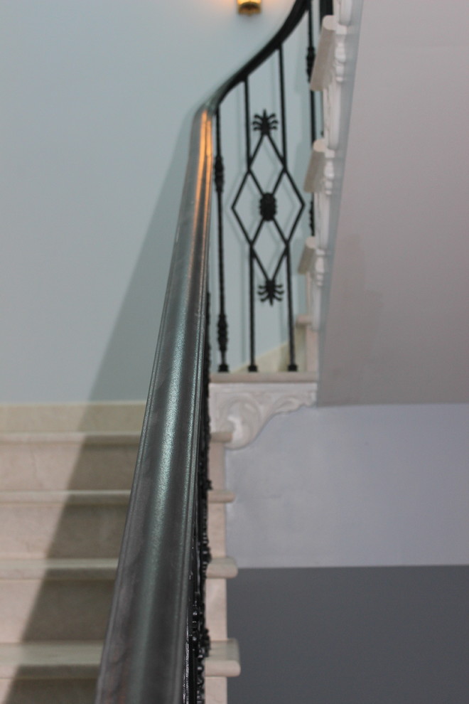 This is an example of a large transitional marble staircase in Other with marble risers and metal railing.