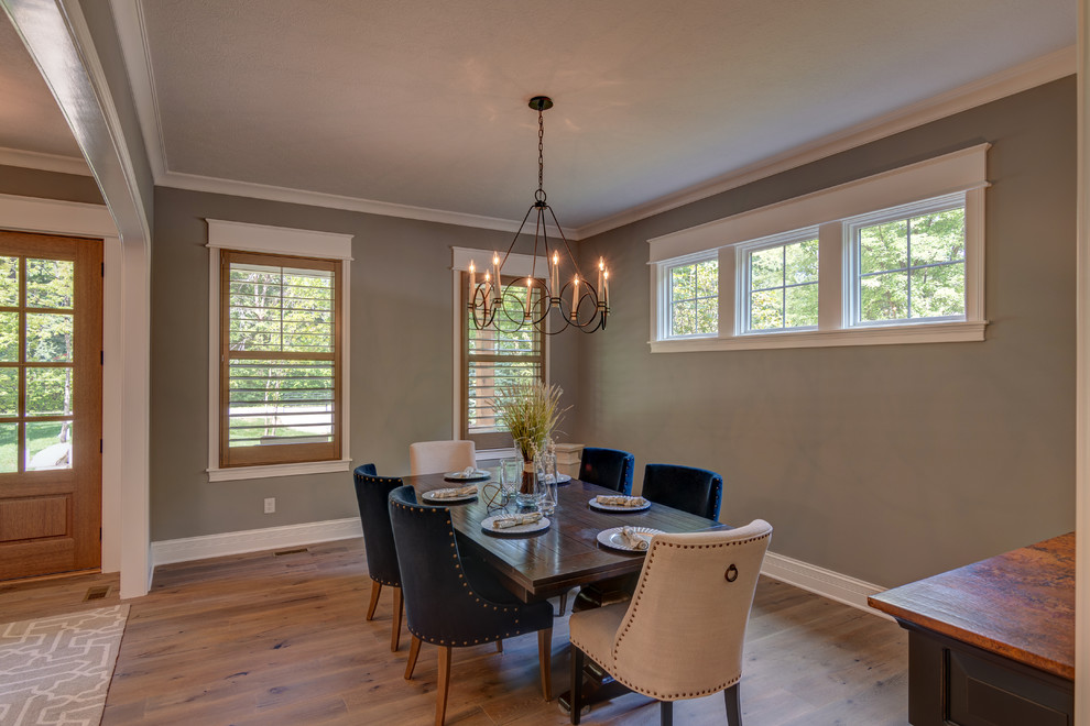 This is an example of an arts and crafts dining room in Indianapolis with grey walls, medium hardwood floors and brown floor.
