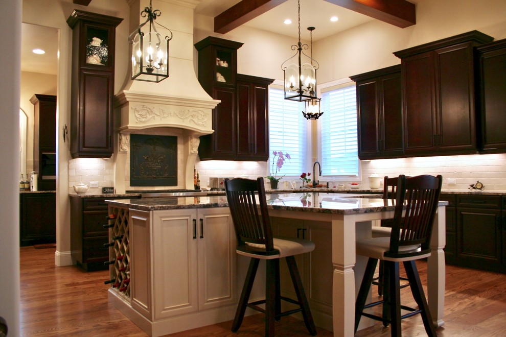 This is an example of an expansive traditional u-shaped kitchen in Denver with raised-panel cabinets, dark wood cabinets, beige splashback, panelled appliances and with island.