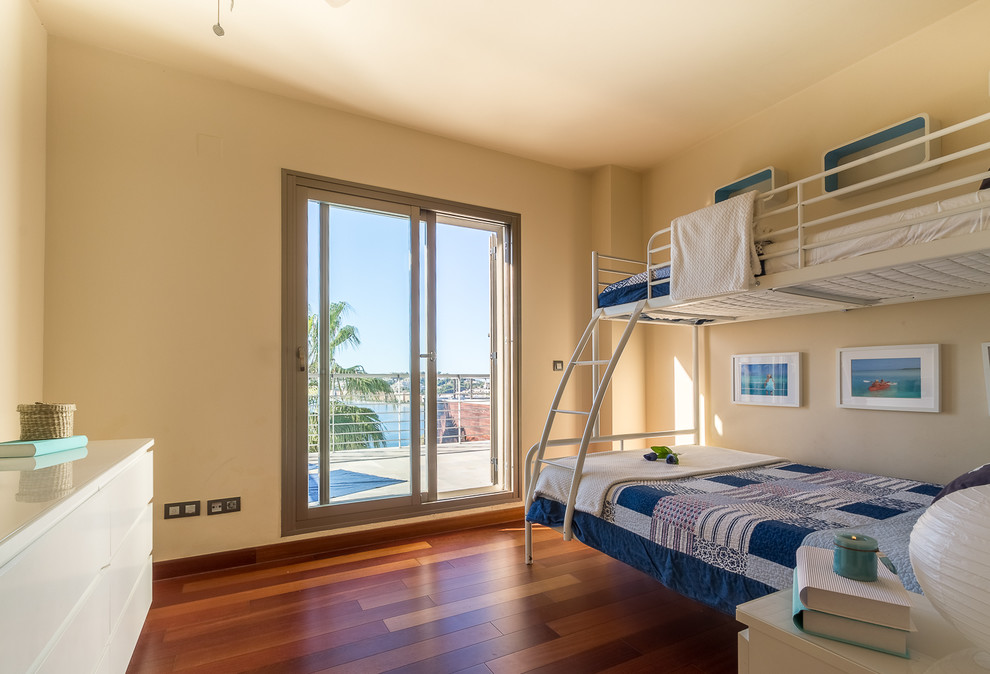 Foto de habitación de invitados mediterránea de tamaño medio con paredes beige, suelo laminado y suelo marrón
