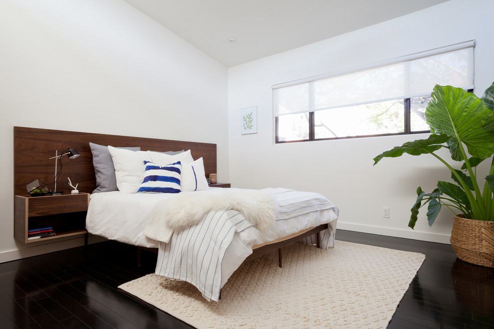 Contemporary master bedroom in Los Angeles with white walls and dark hardwood floors.