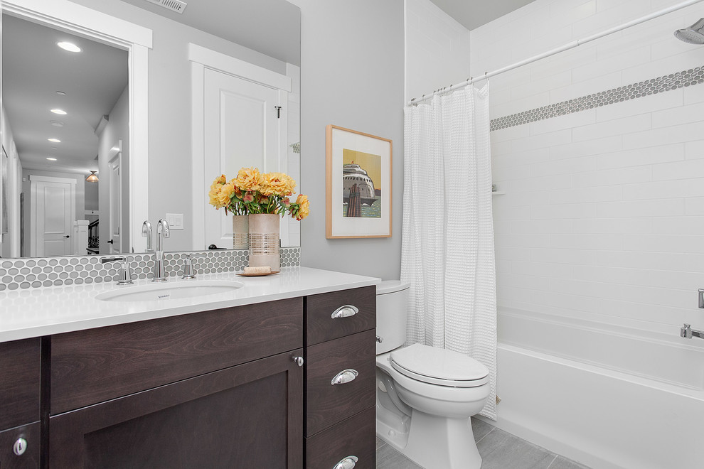 Photo of a mid-sized transitional bathroom in Seattle with shaker cabinets, dark wood cabinets, a shower/bathtub combo, a two-piece toilet, grey walls, an undermount sink, engineered quartz benchtops, an alcove tub, white tile, grey floor and a shower curtain.