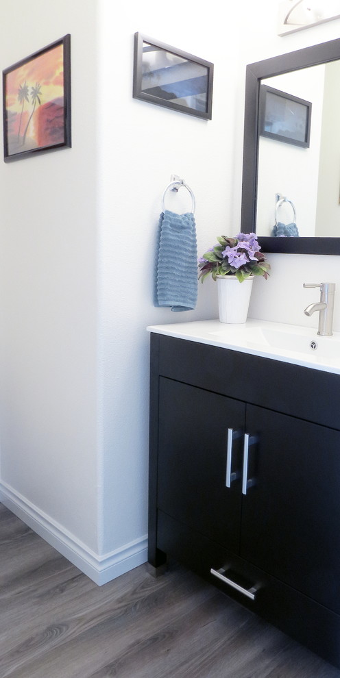 Small transitional medium tone wood floor bathroom photo with flat-panel cabinets, dark wood cabinets, white walls and quartz countertops