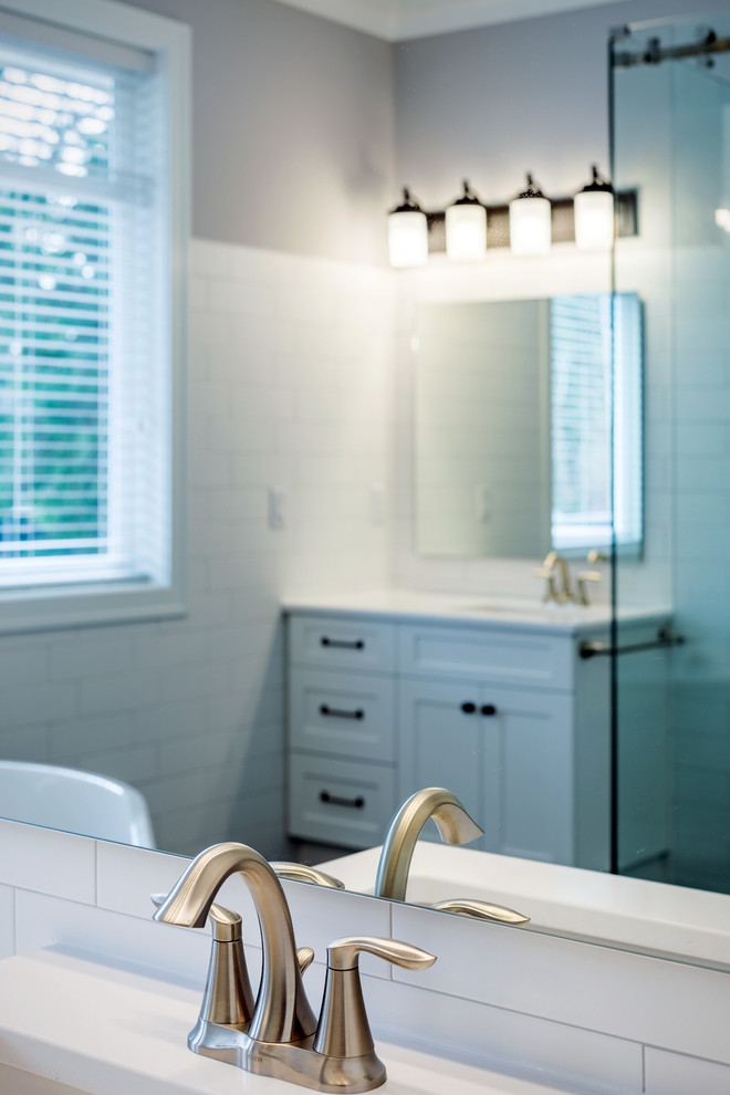Inspiration for a mid-sized traditional master bathroom in Other with shaker cabinets, white cabinets, a freestanding tub, a corner shower, a two-piece toilet, white tile, subway tile, blue walls, ceramic floors, an undermount sink, quartzite benchtops, black floor, a sliding shower screen and white benchtops.