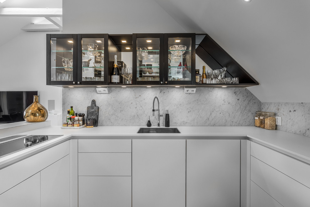 Small contemporary u-shaped kitchen in Stockholm with a single-bowl sink, flat-panel cabinets, white cabinets, grey splashback, marble splashback, no island and white benchtop.