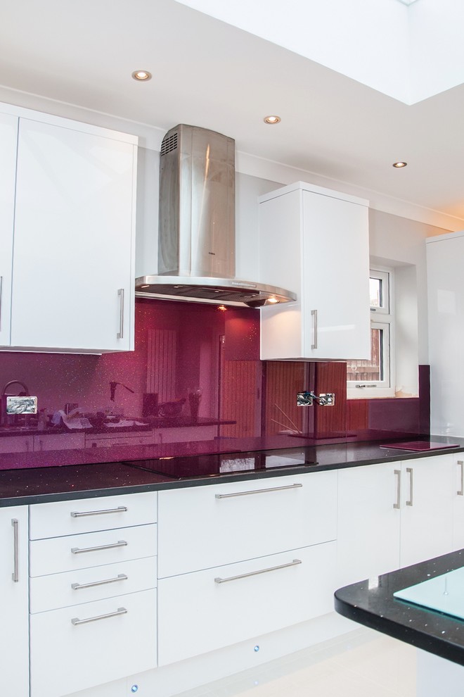Modern kitchen in Hertfordshire with pink splashback and glass sheet splashback.