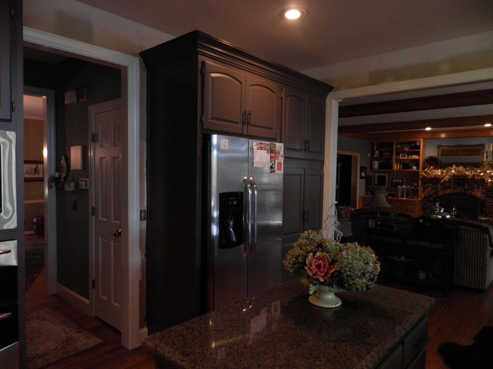 This is an example of a traditional u-shaped kitchen in Kansas City with recessed-panel cabinets, brown cabinets, stainless steel appliances, light hardwood floors, with island, an undermount sink and glass sheet splashback.
