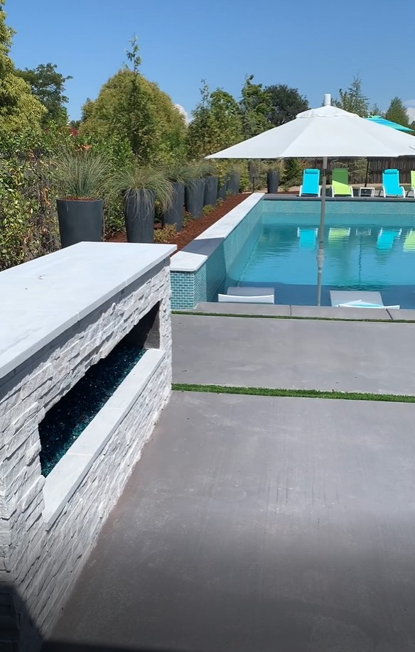 Medium sized classic back rectangular swimming pool in Sacramento with concrete slabs.