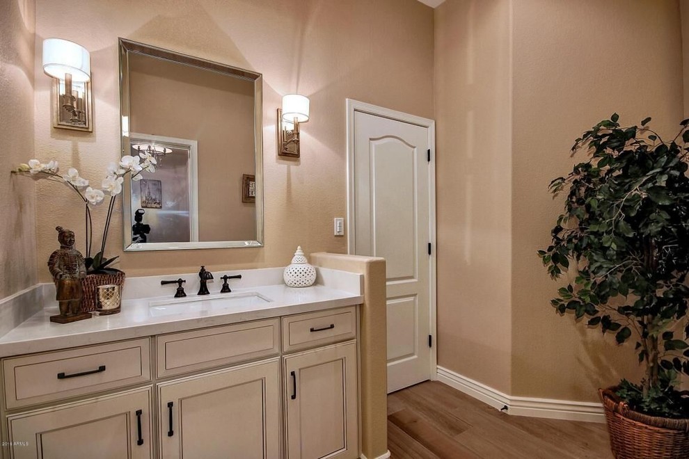 Inspiration for a mid-sized transitional medium tone wood floor and brown floor bathroom remodel in Phoenix with recessed-panel cabinets, yellow cabinets, brown walls and an undermount sink