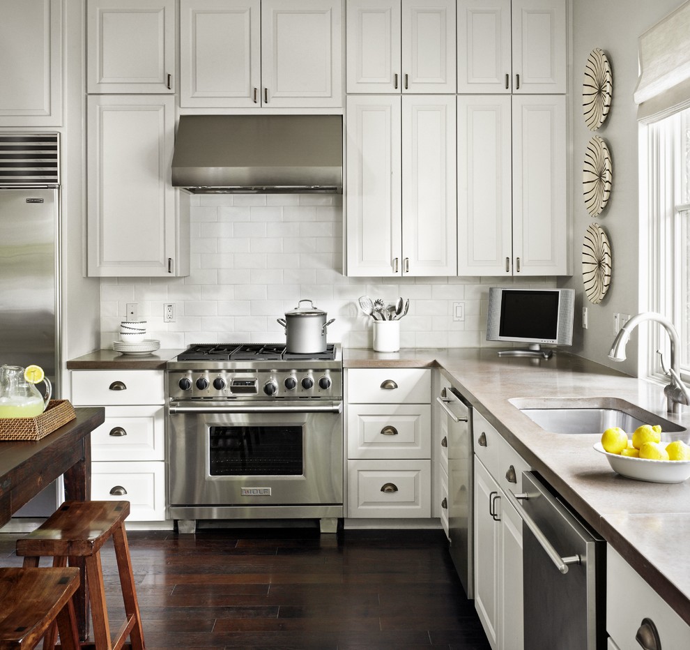 Design ideas for a traditional l-shaped kitchen in Austin with stainless steel appliances, subway tile splashback, an undermount sink, concrete benchtops, raised-panel cabinets, white cabinets and white splashback.