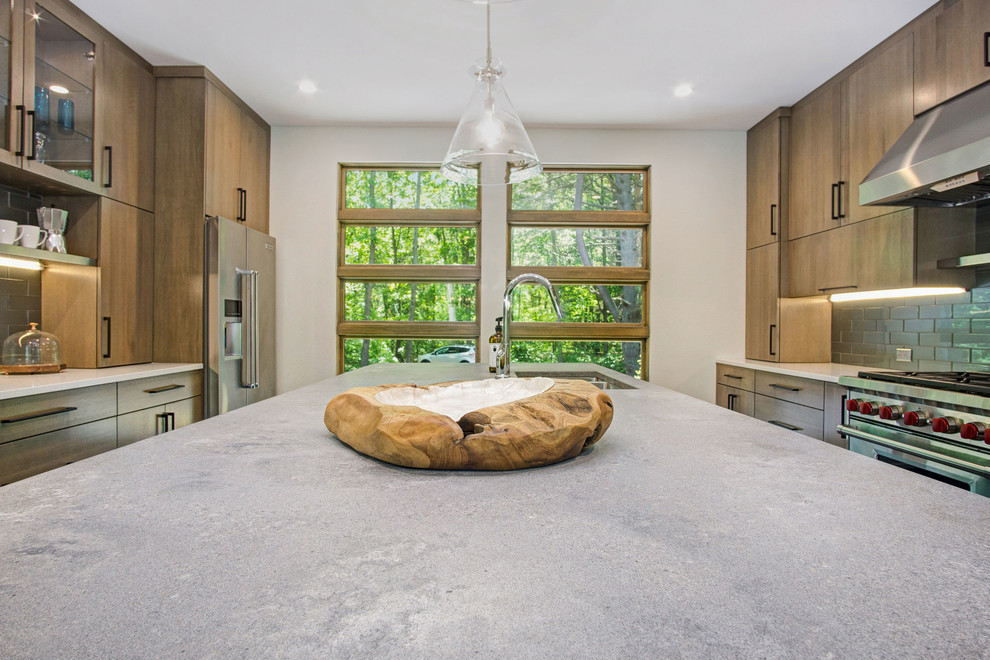 Inspiration for a rustic medium tone wood floor kitchen remodel in Grand Rapids with an undermount sink, flat-panel cabinets, quartz countertops, green backsplash, glass tile backsplash and stainless steel appliances