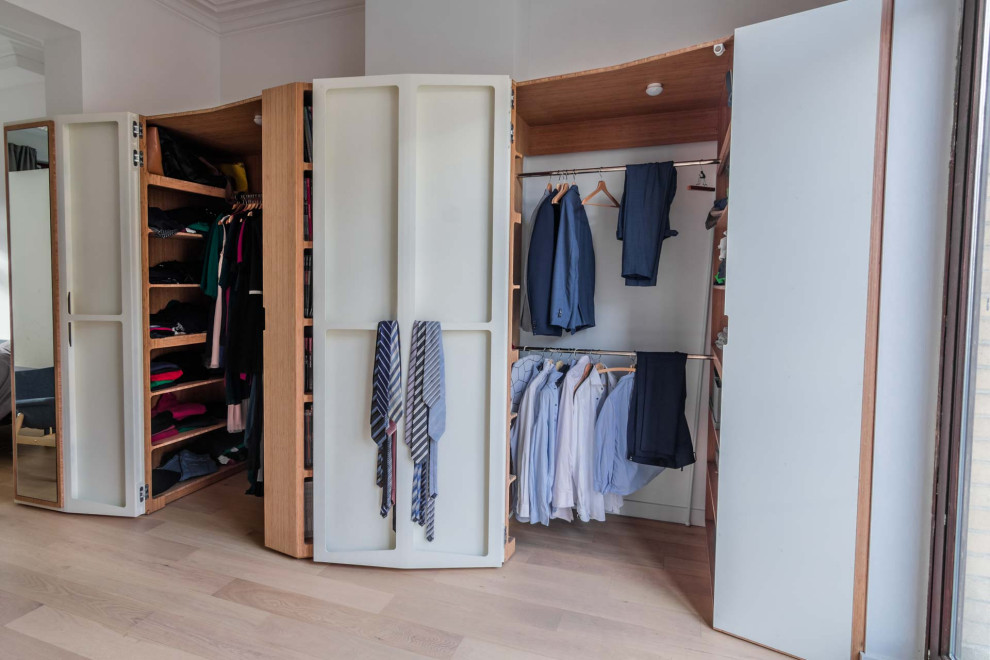 This is an example of an expansive contemporary gender neutral built-in wardrobe in Paris with beaded cabinets, white cabinets, light hardwood flooring, beige floors and a drop ceiling.