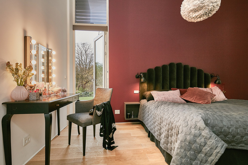 Mid-sized contemporary bedroom in Copenhagen with red walls, light hardwood floors and beige floor.