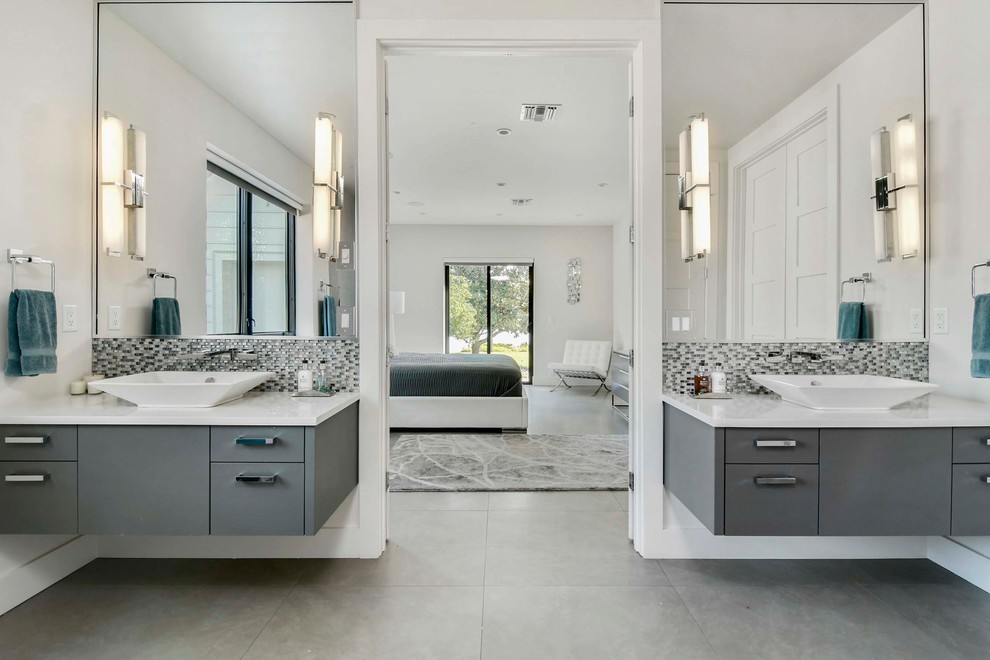 Photo of a large contemporary master bathroom in Orlando with flat-panel cabinets, grey cabinets, an alcove shower, a one-piece toilet, gray tile, glass tile, white walls, porcelain floors, a vessel sink, engineered quartz benchtops and grey floor.