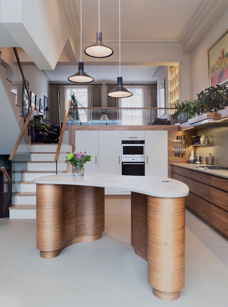Mid-sized contemporary l-shaped kitchen in London with an undermount sink, flat-panel cabinets, medium wood cabinets, stainless steel appliances, with island, grey floor and white benchtop.