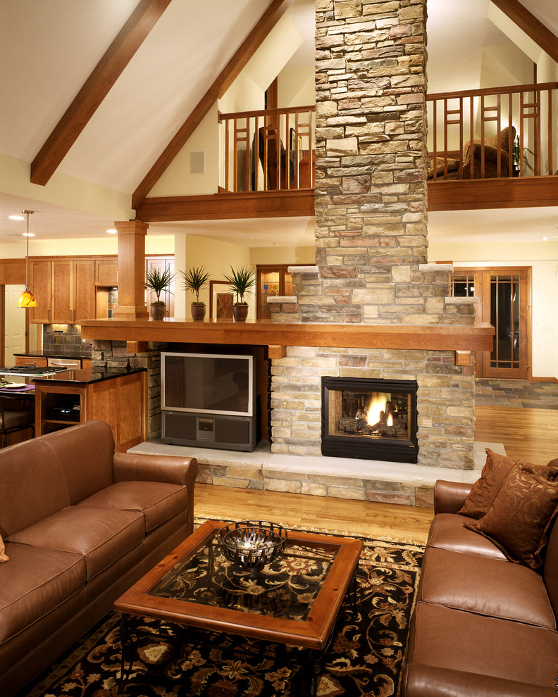 Inspiration for a large country living room in Minneapolis with white walls, medium hardwood floors, a two-sided fireplace, a stone fireplace surround and a freestanding tv.