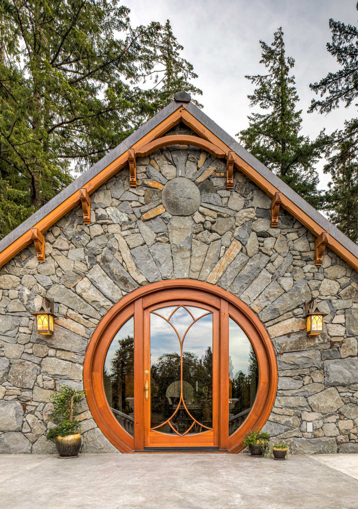 Idée de décoration pour une façade de Tiny House grise bohème en pierre de plain-pied avec un toit à deux pans, un toit en tuile et un toit gris.