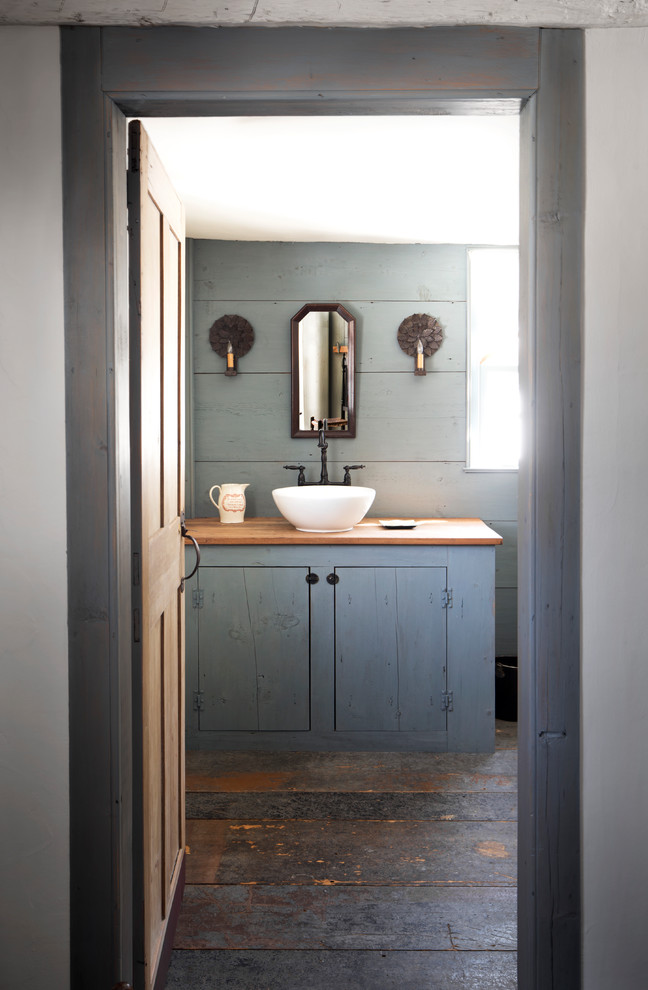 This is an example of a country bathroom in New York with grey cabinets, grey walls, dark hardwood floors, a vessel sink, brown floor and flat-panel cabinets.