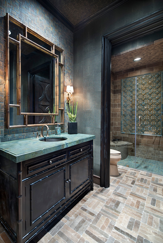 Photo of a mediterranean 3/4 bathroom in Houston with dark wood cabinets, a curbless shower, blue tile, brown tile, green tile, mosaic tile, green walls, mosaic tile floors, an undermount sink, beige floor, a hinged shower door, turquoise benchtops and recessed-panel cabinets.